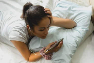 Cep telefonu kullanarak yatakta yatan portre karma yarış genç kız.