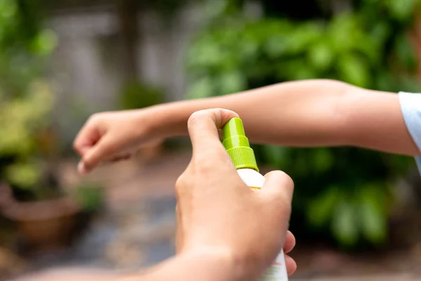 Pai pulverizando repelentes de insetos em seu braço filho no jardim . — Fotografia de Stock