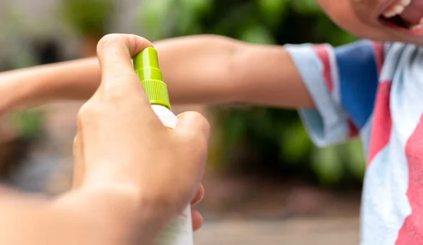 Vater sprüht seinem Sohn im Garten Insektenschutzmittel auf den Arm. — Stockfoto