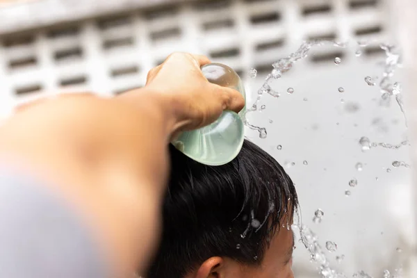 Vater zerbricht Wasserballon über Kopf seines Sohnes. — Stockfoto