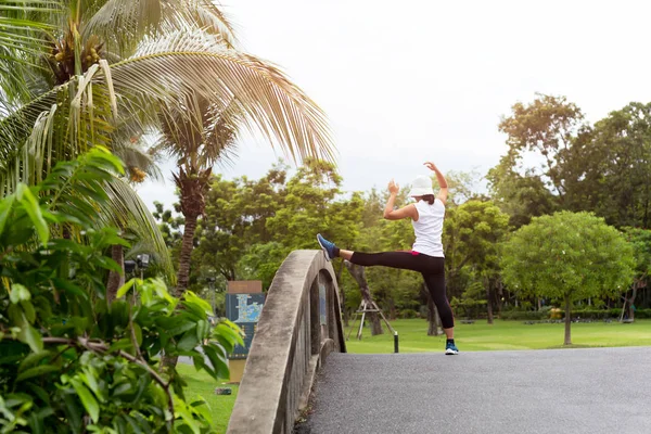 Femme fait des étirements sur le pont dans un parc le matin . — Photo