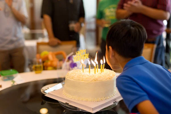 Kleiner Junge feiert Geburtstag und bläst Kerzen auf seine Torte mit der Familie. — Stockfoto