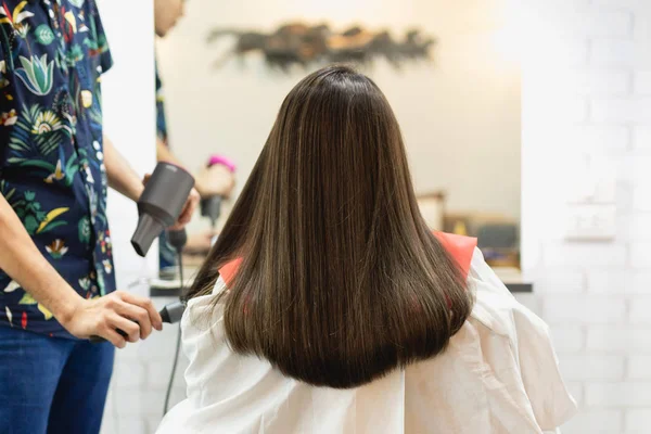 Stylist hairdresser making hairstyle using hair dryer blowing on customer hair at beauty salon. — Stock Photo, Image