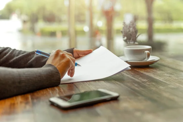 Busineswoman hand holding pen over  paperwork on wooden table