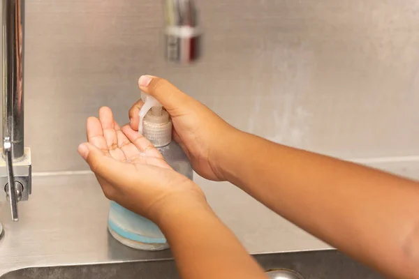 Pulizia bambini mano con gel liquido nel lavello della cucina . — Foto Stock