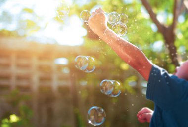 Bulanık kavramı genç çocuk güneş ışığı ile Bahçe kabarcık oyuncak ile oyun.