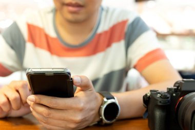 Ahşap masa üzerinde Dslr fotoğraf makinesi ile acımak telefon kullanarak eller mans.