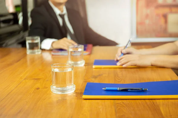Affärsmän möte vid konferens med glas wter och anteckningsbok på träbord. — Stockfoto