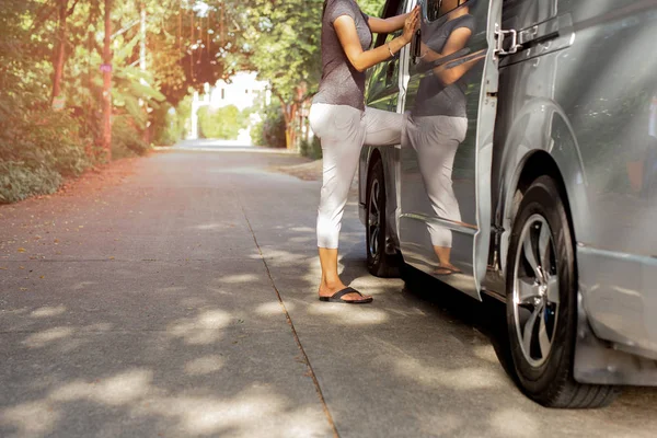 Woman passenger wearing flip flops getting on the bus on vacation.