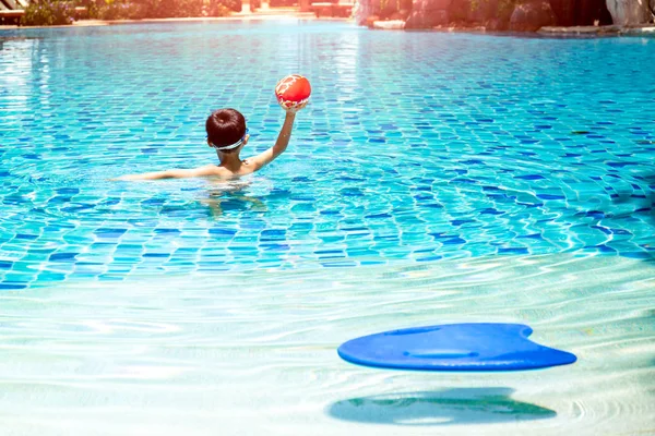 Little boy playing a ball game in swimming pool in summer. — Stock Photo, Image