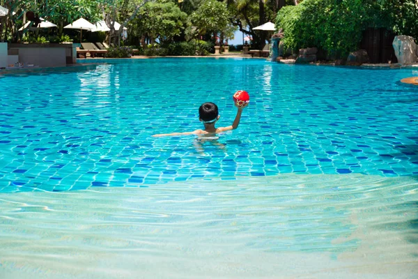 Menino jogando um jogo de bola na piscina no verão . — Fotografia de Stock