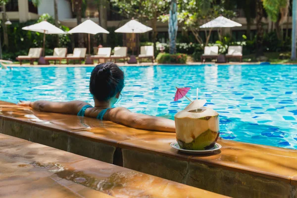 Mulher relaxar tomando bebida de coco e ouvir música na piscina em férias . — Fotografia de Stock