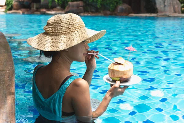 Mulher asiática com chapéu tendo bebida de coco na piscina de férias . — Fotografia de Stock