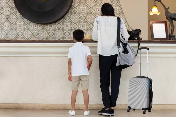 Familie Wert Mutter und Sohn checken mit Koffer im Urlaub im Hotel ein. — Stockfoto