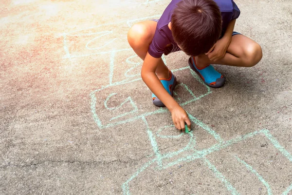 Niño jugando hopscotch juego en el suelo de hormigón al aire libre en verano . —  Fotos de Stock