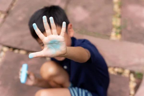 Menino com a mão suja de giz azul depois de desenhar . — Fotografia de Stock
