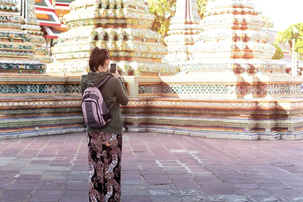 Mujeres turísticas no identificadas tomando fotos con teléfono celular visitando templo tailandés y en Bangkok Tailandia . — Foto de Stock