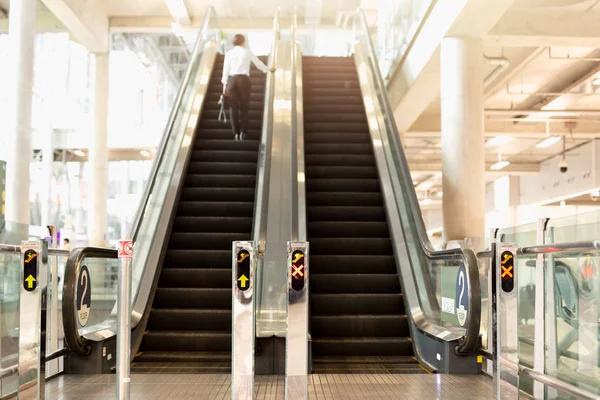 机场自动扶梯与模糊的女背包客站在后台 — 图库照片