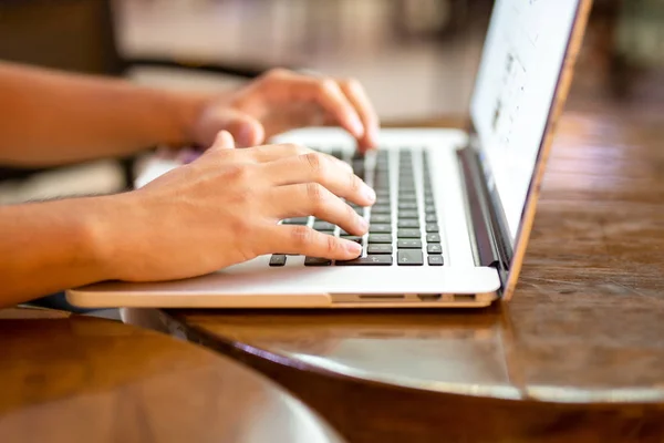 Man working on laptop with mug of coffee in cafe shot in low lig — Stock Photo, Image