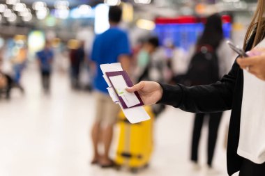 Kadın el holding pasaport ve biniş kartı bulanıklık arka planda havaalanında.