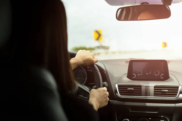 Vrouw die auto met teken van scherpe bochten vooruit te drijven op de weg. — Stockfoto