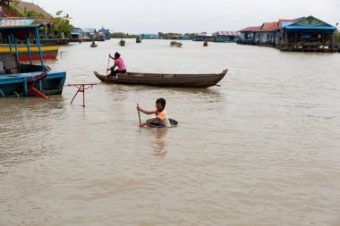 Ağustos: 29: 2018 - Siem Reap, Kamboçya - anne ve oğlu ile çocuk kullanım Havzası olarak Tonle Sap Gölü bir tekne tekne..