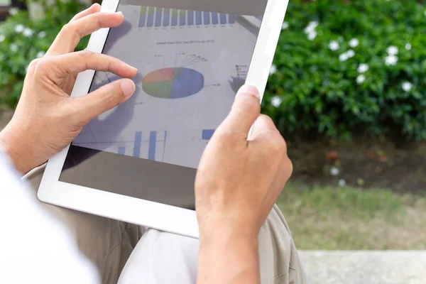 Businessman hands using tablet screen show green graph while working at home in the garden