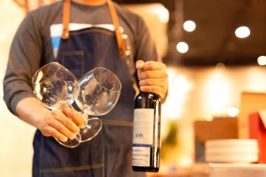 Garson kanadında cam şişe kırmızı şarap arka planda eldir