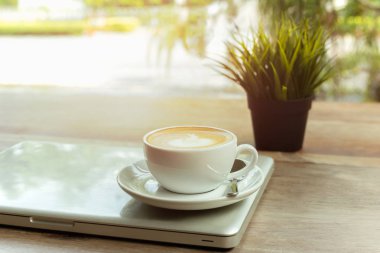 Ahşap masa ve sabah ışık dizüstü bilgisayar ile kahve fincanı