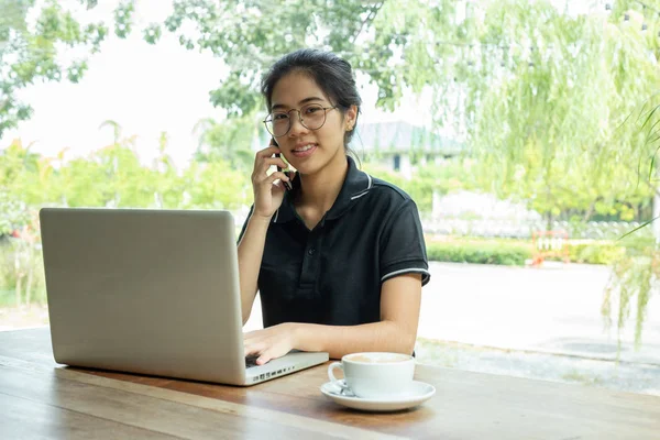 Fiatal Kávézóban Használ Egy Laptop Egy Mobiltelefonon Beszél — Stock Fotó