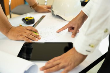 Ekip çalışması Asya mühendis ve aechitectuer el bluepring kroki masaya gösteren binanın planı üzerinde çalışma.