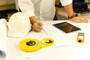 El ile tablet bilgisayar ofiste tabloda çalışma planı üzerinde çalışan mimar.