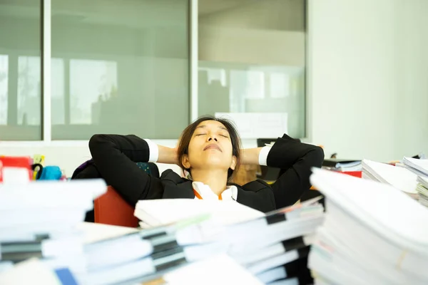 Exhausted Businesswoman sleeping on desk in office with pile of paperwok