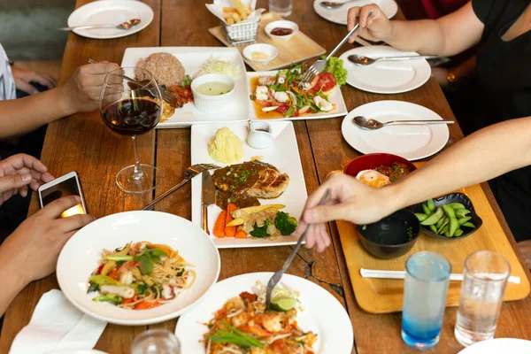 Group of friends hands with fork having fun eating variety food on the table