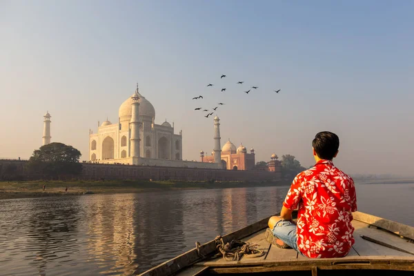 Homem assistindo pôr do sol sobre Taj Mahal de um barco de madeira com pássaro voando sobre . — Fotografia de Stock