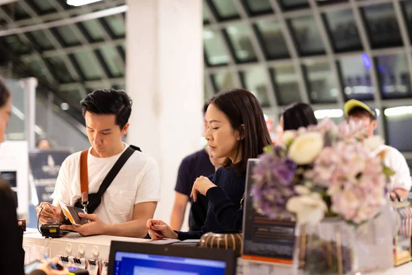 Asian couple signing bill for hotel room at reception