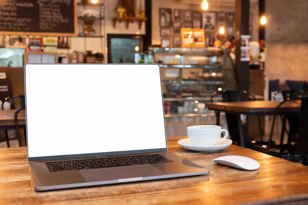Blank screen laptop with mouse and coffee cup on wooden table in coffe shop