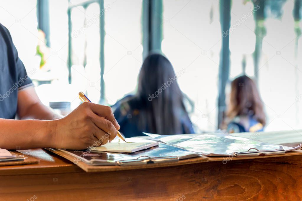 Waiter writing down customer order at the counter bar in cafe