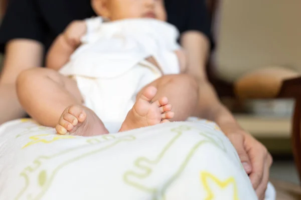 Baby feet resting on mother lap in the house