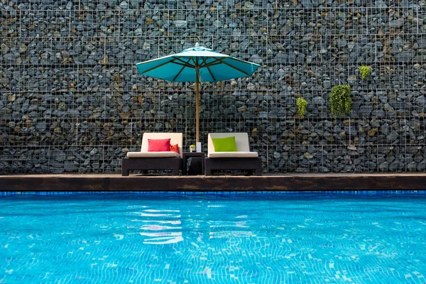 Tumbonas con sombrilla cerca de la piscina en vacaciones de verano . — Foto de Stock