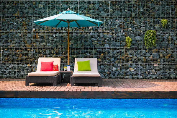 Tumbonas con sombrilla cerca de la piscina en vacaciones de verano . — Foto de Stock