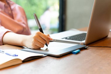 Grafik tasarımcı masanın üstünde laptop ile dijital tablet kullanma.