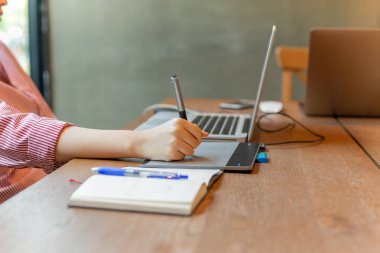 Grafik tasarımcı masanın üstünde laptop ile dijital tablet kullanma.