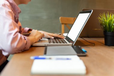 Ahşap masa üstünde laptop üzerinde çalışan genç kadın.