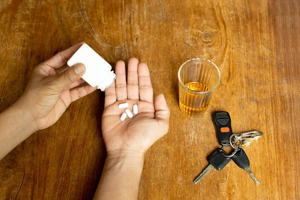 Man holding pills and glass of alcohol with car keys on wooden t — Stock Photo, Image