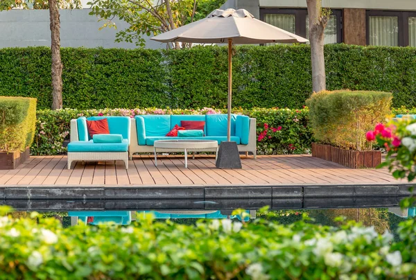 Amplio patio terraza con muebles de ratán en el jardín con sombrilla . — Foto de Stock