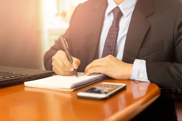 Businessman hand writing on notebook with laptop computer on the table. — Stock Photo, Image