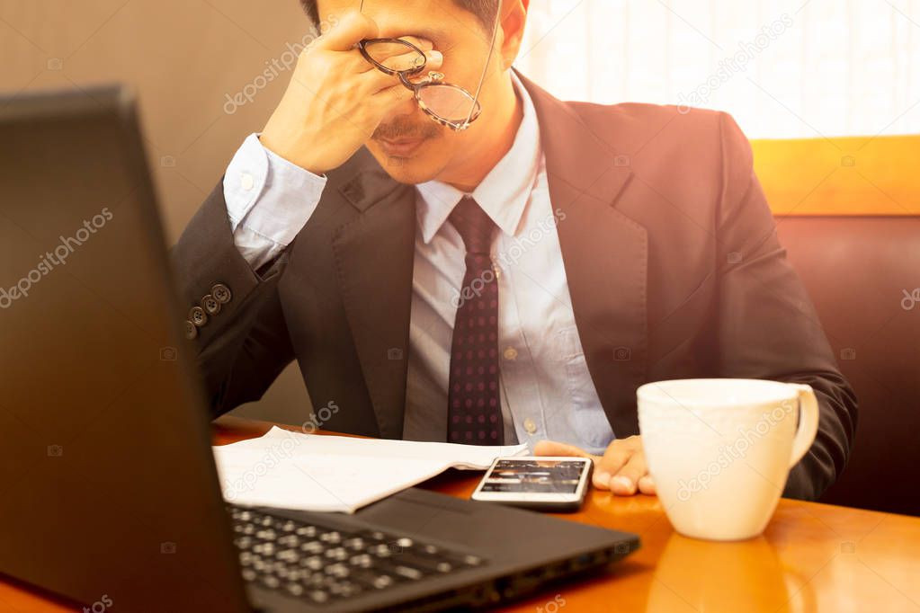 Stress businessman in suit holding eyeglasses rubbing his eyes a