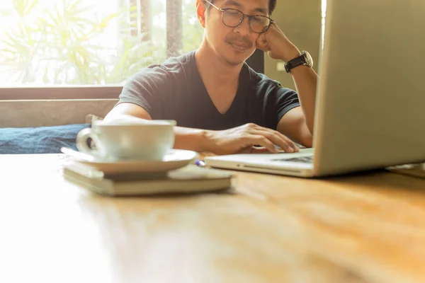 Serious man works with laptop while sitting in cafe with coffee on table.