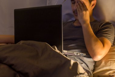 Yorgun adam yatakta el ile gece mesaiye rub gözleri.